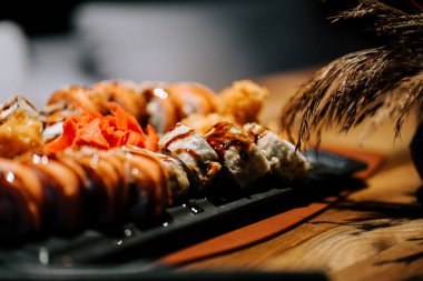 Suşi tabağı yemek boyunca ahşap bir masada garnitür ve sosla sunuldu.