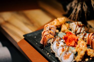 Sıcak bir restoranda, siyah bir tabakta servis edilen taze hazırlanmış suşi tabağı.
