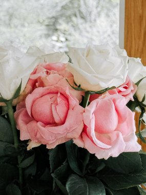 Pembe ve beyaz güller güzel bir bukette düzenlenir kapalı bir yerde güneşli bir günde