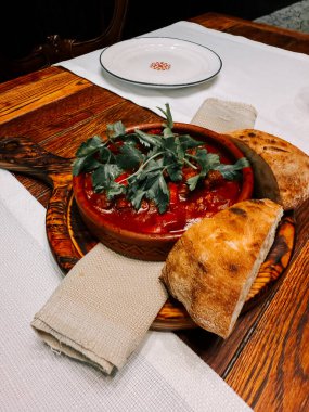 Sıcak bir ortamda, ahşap bir masada taze ekmekle servis edilen lezzetli bir yemek.