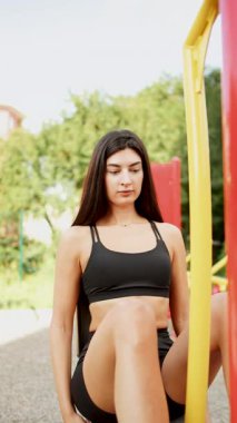 Genç bir kadın güneşli bir havada parkta spor malzemelerini kullanarak dışarıda egzersiz yapıyor.