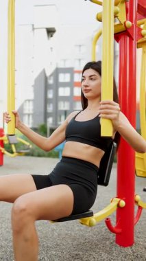 Güneşli bir havada modern şehir ortamında açık hava spor salonunda egzersiz yapan bir kadın.