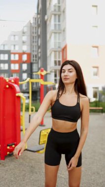 Genç bir kadın güneşli bir öğleden sonra modern spor salonunda egzersiz yapıyor.