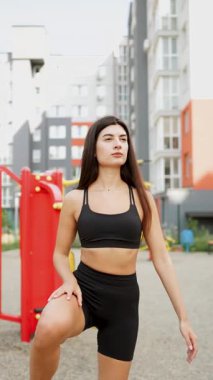 Güneşli bir günde şehir parkında egzersiz yapan genç bir kadın.