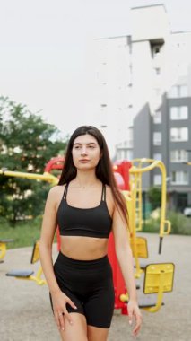 Güneşli bir öğleden sonra şehir parkındaki spor salonunda egzersiz yapan genç bir kadın.