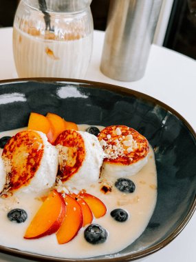 Modern bir yemek masasında taze meyve ve kremalı sosla nefis bir kahvaltı kasesi.