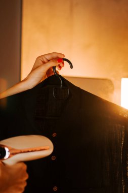 Kadın, gömleğini sıcak ve davetkar bir şekilde evde yenilemek için buharlı giysi kullanıyor.