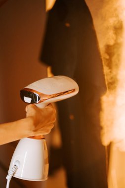 Kadın, gömleğindeki kırışıklıkları, iç mekânda rahat bir buharlı gömlekle hiç zorlanmadan çıkarıyor.