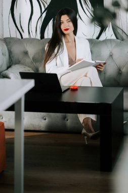 Şık giyinmiş bir kadın, modern oturma odasında sanatsal dekorla notlar alıyor.