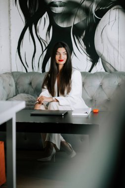 Modern salon ortamında zarif bir kadın sanatsal arkaplana karşı zarif pozlar veriyor.