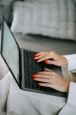 Kadın yatakta otururken dizüstü bilgisayar kullanıyor, rahat bir yerde işine ya da iletişim görevlerine odaklanıyor