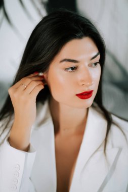 Modadan esinlenilmiş bir portre oturumu sırasında şık bir kıyafet içinde çarpıcı kırmızı dudaklı zarif bir kadın.