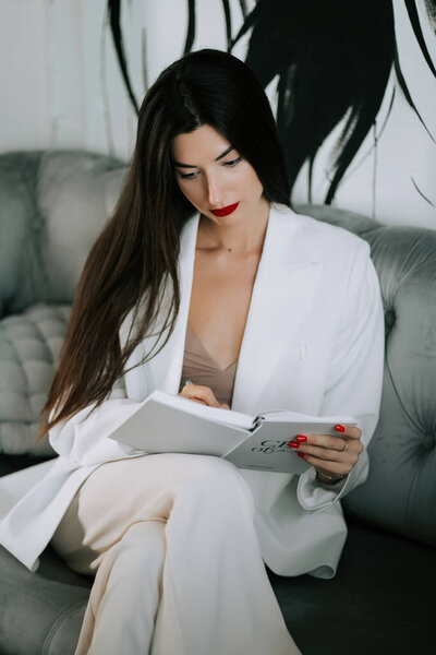 Elegant woman reading in a stylish indoor setting at a contemporary lounge