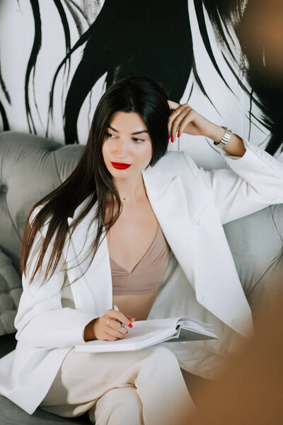 Businesswoman brainstorming ideas in stylish office setting with artistic backdrop in the afternoon
