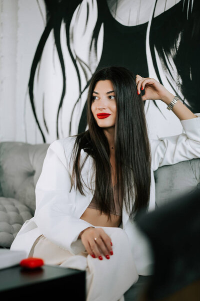 Stylish woman relaxing on a sofa in a contemporary art-inspired space during the day