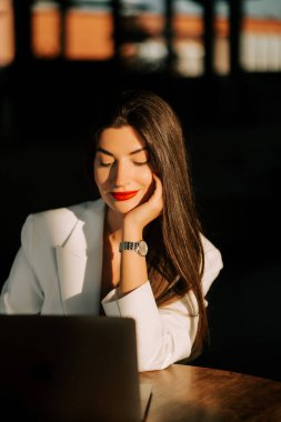 Odaklanmış kadın, güneşli bir odada dizüstü bilgisayarın başında çalışırken sessiz bir anın tadını çıkarıyor.