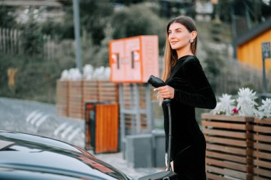 Gündüz vakti modern benzin istasyonunda şık giyinmiş bir kadın.