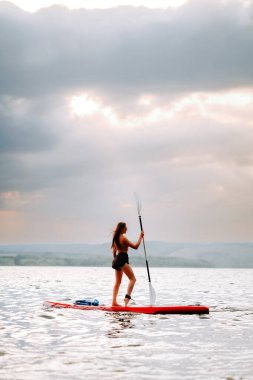 Bulutlu bir akşamda sakin bir stand-up deneyimi yaşayan bir kadın.