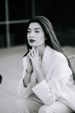 Beyaz takım elbiseli kadın derin düşüncelere daldı.