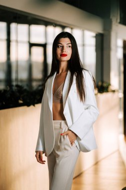 Model modern iç mekanlarda zarif pozlar veriyor. Yumuşak öğleden sonra ışığı altında şık kıyafetler giyiyor.