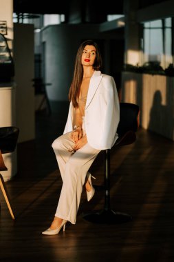 İş adamı, öğleden sonra günışığında modern bir ofiste güven içinde oturuyor.