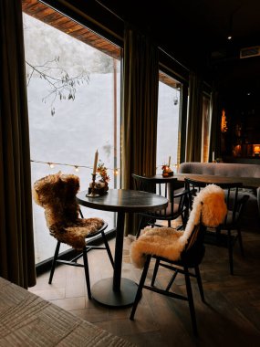 Cozy indoor cafe setting with fur chairs and a view of snow outside