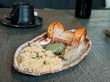 Kahvaltı tabağında yumurta, tost ve bir kafede servis ediliyor.