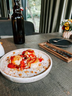 Kırsal bir masada taze çilek ve krem şantili lezzetli bir tatlı sergilenir.