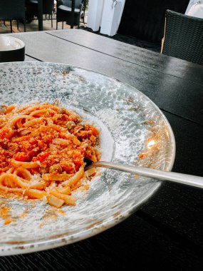 Samimi bir açık hava yemek ortamında zarif bir tabakta servis edilen makarna.