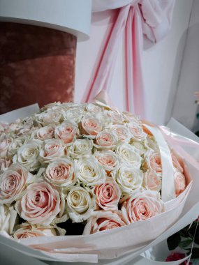 Gün ışığında bir çiçekçide sergilenen pembe ve beyaz güller.