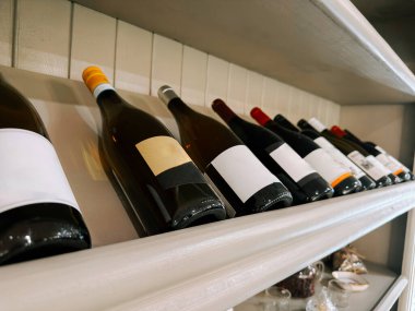 Şarap şişelerinin seçimi ahşap bir rafta konforlu bir ortamda tatmak için düzenlenmiştir.