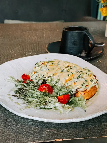 Cafe 'deki ahşap masada salata ve kahve ile nefis açık yüzlü sandviç.