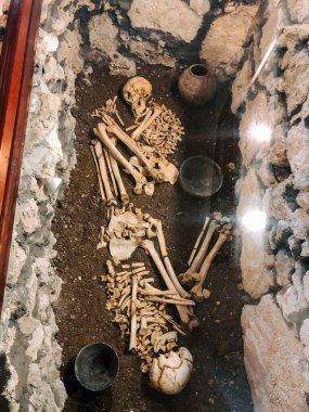 Ancient burial site reveals skeleton and artifacts in a stone enclosure in archaeological excavation