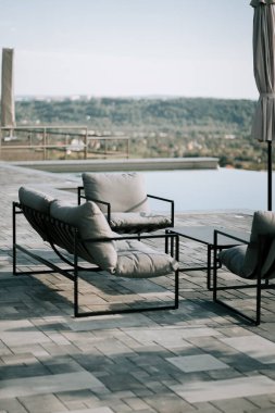 Yüzme havuzunun yakınındaki manzaraya bakan rahat bir oturma alanı.
