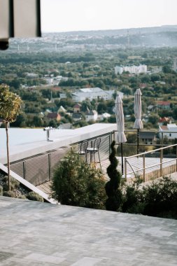 Güneşli bir günde yemyeşil bir vadi üzerinde çarpıcı manzaralı çağdaş bir açık hava terası.