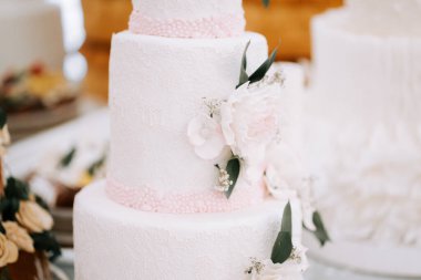 Çiçek süslemeli zarif düğün pastası güzel bir mekanda düğün resepsiyonunda sergileniyor.