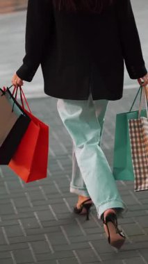 Alışveriş torbaları, öğleden sonra kalabalık bir alışveriş bölgesinde yürürken sallanıyor.