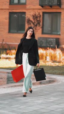 Güneşli bir günde şehir parkında şık bir kadın alışveriş yapıyor.