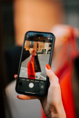 Kadın şehir caddesinde şık kırmızı bir elbiseyle alışveriş yaparken anı yakalıyor.