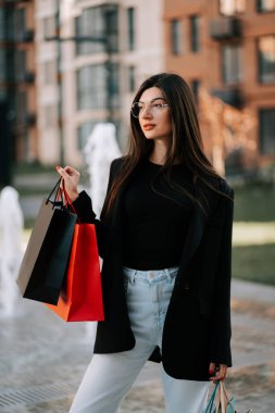 Kadınlar güneşli bir günde ellerinde şık çantalarla dışarıda alışveriş yapmayı severler.