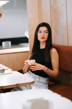 Öğleden sonra modern bir kafede keyfi bir şekilde oturan bir kadın.