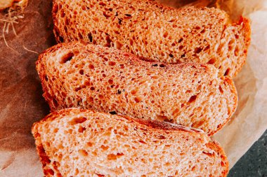 Sıcak bir mutfak ortamında parşömen kağıdına taze ekmek dilimleri.