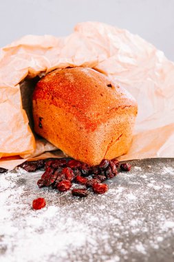 Kurutulmuş meyvelerle taze pişmiş somun gri bir yüzeye dökülür.