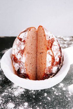 Freshly baked round bread with a dusting of flour and a sliced view showcasing its soft center