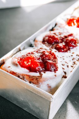 Tatlı vişne sosu ve kremalı kremayla kaplı yumuşak ekmekler içeren lezzetli bir tatlı.