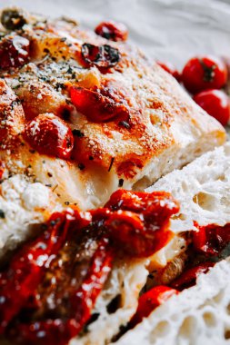 Delicious homemade bread topped with sun-dried tomatoes and herbs placed on a rustic surface