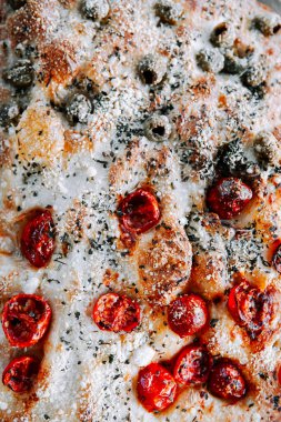 Baked flatbread topped with roasted tomatoes and herbs in a warm kitchen setting