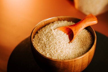 Tahta bir kâse içinde kuskus. Mutfak masasında tahta bir kaşık.