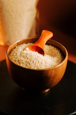 Tahta bir kasede pişmemiş kuskus, ahşap bir kepçeyle, yemek hazırlamak için mükemmel.