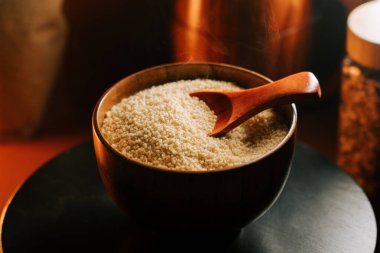 Tahta bir kasede kuskus, karanlık bir masada kaşıkla.